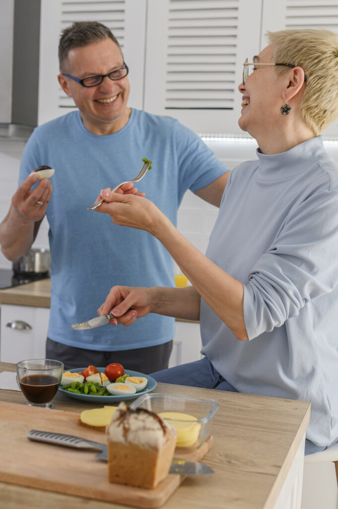 cheerful-middleaged-couple-smiling-while-cooking-lunch-together-home-healthfy-retired-lifestyle